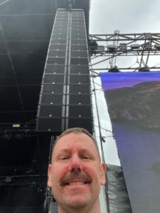 Steve Litscher FOH and TM standing in front of LAcoustics K1 PA system in Australia while on tour